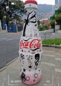 Escultura publicitaria de gran formato en forma de botella de Coca-Cola intervenida artísticamente con gráficos blancos, negros y rojos, fabricada mediante impresión 3D por CR Studio 3D en Medellín.
