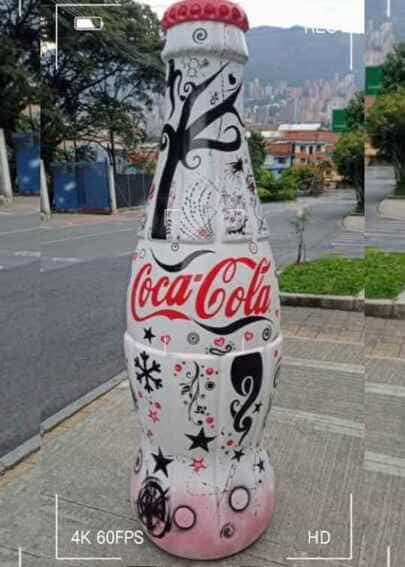Escultura publicitaria de gran formato en forma de botella de Coca-Cola intervenida artísticamente con gráficos blancos, negros y rojos, fabricada mediante impresión 3D por CR Studio 3D en Medellín.