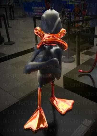 Figura coleccionable del Pato Lucas de Looney Tunes con brazos cruzados y acabado negro mate con detalles metalizados naranjas sobre un pedestal en una exhibición, fabricada mediante impresión 3D por CR Studio 3D en Medellín.