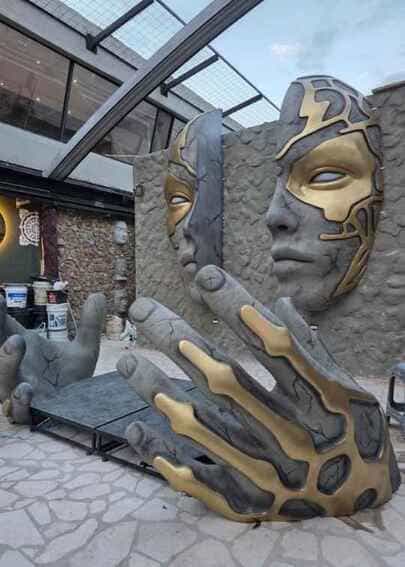 tematización monumental del escenario de DJ en Zenith Rooftop con rostro dividido y manos gigantes con acabados dorados y piedra, fabricada por CR Studio 3D en Medellín.